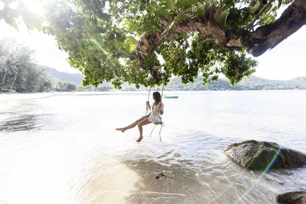 美丽的年轻女性旅行者在热带岛屿上荡秋千在惊人的风景的背景下 — 图库照片