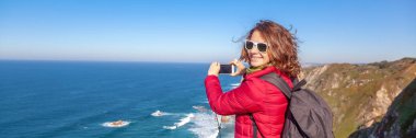 Bir cep telefonu, Portekiz seyahatini kış manzara güzel genç kadın ceket Cape Roca'da vuruyor