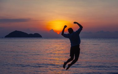 Silhouette bir adam sahil üzerinde günbatımında, dostum atlama ve doğa kavramı, güzellik yaşam tarzı Özgürlük tatil seyahat