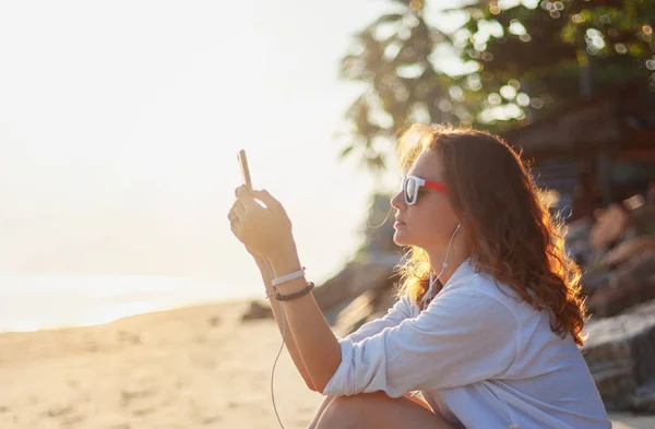 Schöne Junge Frau Sitzt Strand Bei Sonnenuntergang Mit Kopfhörern Und — Stockfoto