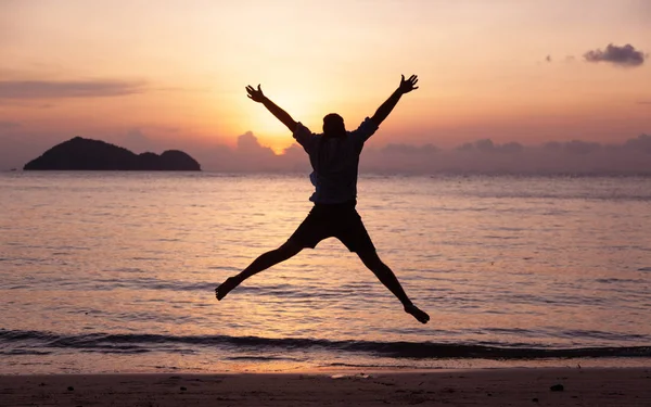 Silhouette of a jumping man on the seashore at sunset, man and nature concept, beauty lifestyle freedom vacation travel