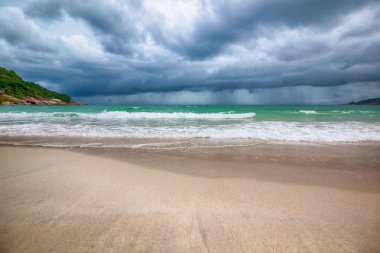 Tropikal bir plaj, karanlık fırtına bulutları, güzel etkileyici manzara, dalgalar ve beyaz kum, iklim değişikliği fırtınası