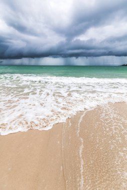 Tropikal bir plaj, karanlık fırtına bulutları, güzel etkileyici manzara, dalgalar ve beyaz kum, iklim değişikliği fırtınası