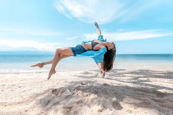 Photograph with the effect of levitation, a young beautiful slim woman hanging in the air against the backdrop of the tropical sea and the beach
