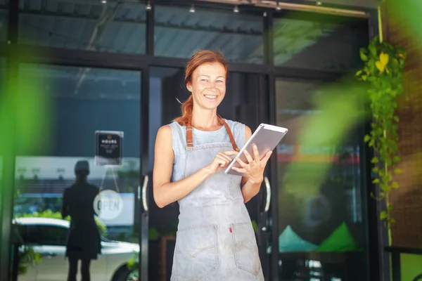 The woman is a waitress in an apron, the cafe owner is holding a tablet with a menu. Small business concept, cafes and restaurants