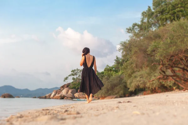 オープン バックと美しいドレスを着た細身の若い女の子は 熱帯の海の海岸を歩く — ストック写真