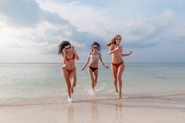 Üç güzel ince mutlu kız sahilde seviniyor ve having fun eğlenmek seyahat
