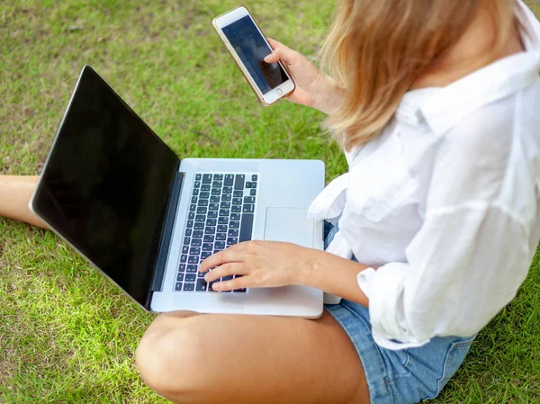 Mooie blonde meisje met een laptop op een groen gazon, het onderwijs en de verre werk — Stockfoto