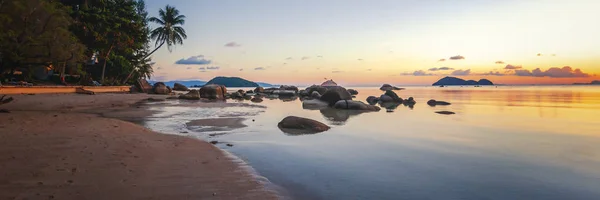 Mar pôr do sol rochas praia no fundo do céu azul. Nascer do sol da noite. Praia de areia com rochas — Fotografia de Stock