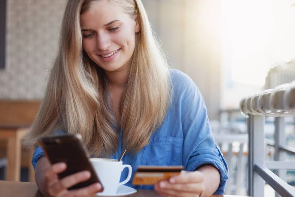Piękna młoda blond dziewczyna kawiarnia z kartą kredytową w jej rękach — Zdjęcie stockowe