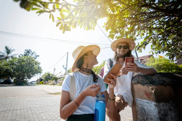 Пара молодих красивих щасливих мандрівників в капелюхах, чоловік і жінка, з мобільними телефонами в руках . — стокове фото