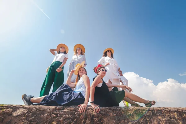 Group of happy joyful young stylish girls travel together, in hats against a blue sky — Stock Photo, Image