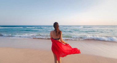 Elinde parlak kırmızı bir eşarp ile bir bikini uzun saçlı güzel genç esmer kadın