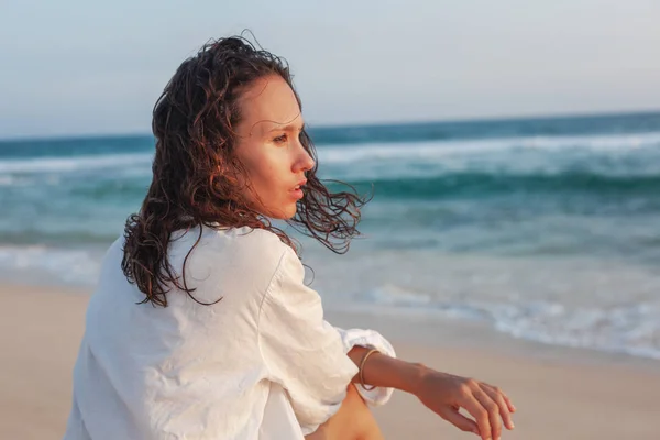 Piękna młoda brunetka kobieta z długimi włosami w białym w białej koszuli na Oceanie o zachodzie słońca — Zdjęcie stockowe