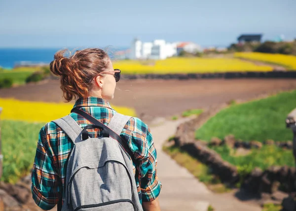 Travel to Jeju Island, South Korea, a young girl tourist walks on the background of blooming field — Stock Photo, Image