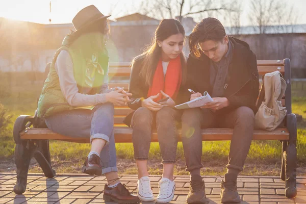 Groupe d'adolescents asiatiques écoliers assis sur un banc dans le parc et préparant des examens — Photo