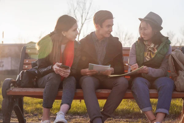 Groupe d'adolescents asiatiques écoliers assis sur un banc dans le parc et préparant des examens — Photo