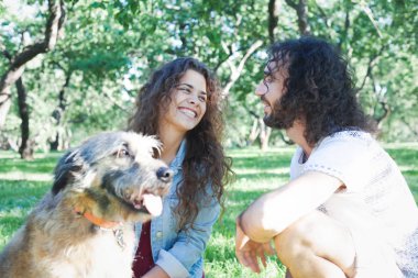 Mutlu güzel kıvırcık genç çift ile çim üzerinde oturur  