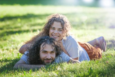 Yaz aylarında yeşil çim üzerinde yatan mutlu genç kıvırcık çift 