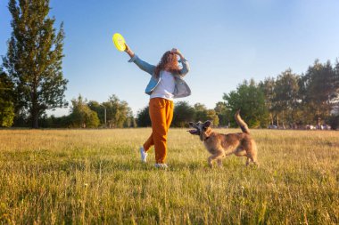 Ergen Güzel kıvırcık kız bir frizbi ile köpeği ile oynuyor 