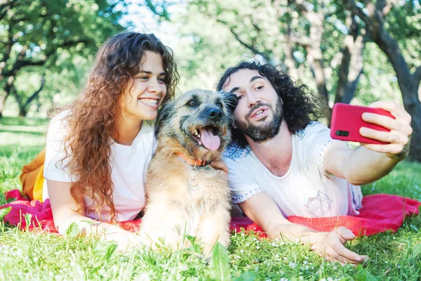 Jonge stijlvolle paar spelen met hond in Park, maken selfie Pho — Stockfoto