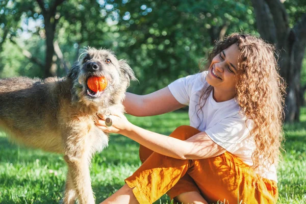 Jong gelukkig charmant meisje spelen met haar hond met een bal in de th — Stockfoto