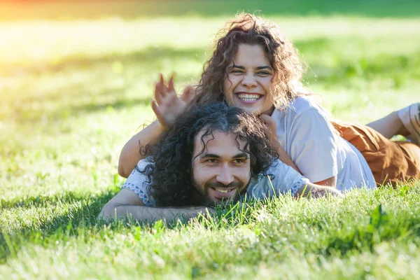 Heureux jeune couple bouclé couché sur l'herbe verte en été — Photo