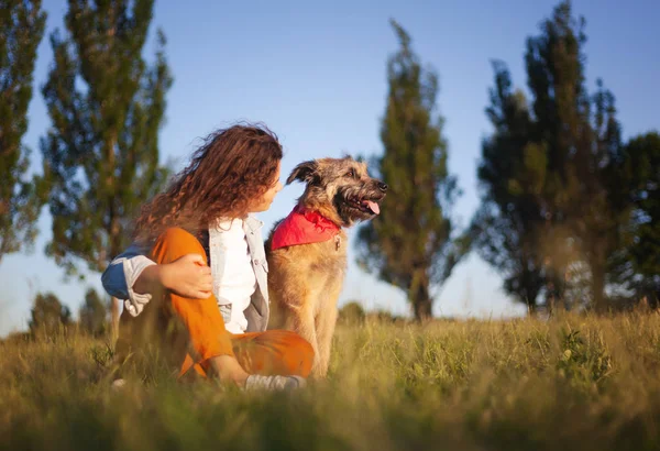 Gelukkig jong krullend meisje met een mooie glimlach met haar hond in th — Stockfoto