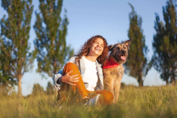 Lycklig ung lockig flicka med ett vackert leende med sin hund i th — Stockfoto