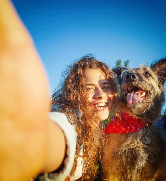 Schöne lustige lockige Mädchen macht ein Selfie mit ihrem zotteligen Hund in — Stockfoto