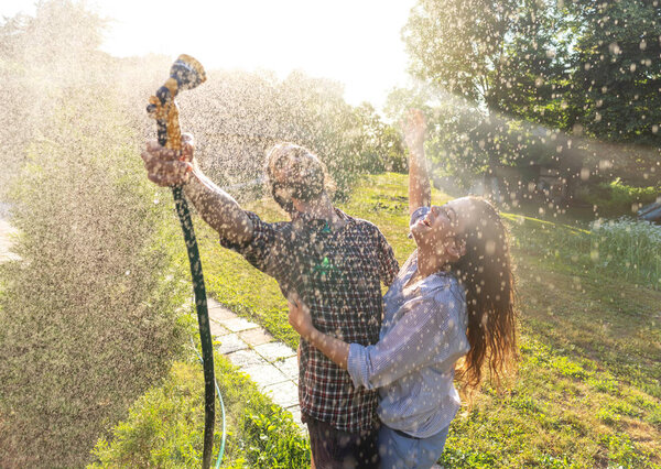 young happy beautiful couple hosing in the garden, summer happin