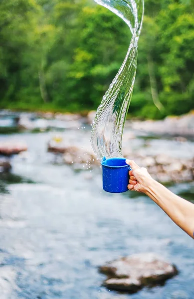 Taza de camping azul con agua clara, salpicaduras en un bosque backgrou —  Fotos de Stock