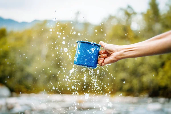 Tazza da campeggio blu con acqua limpida, spruzzi su un backgrou foresta — Foto Stock