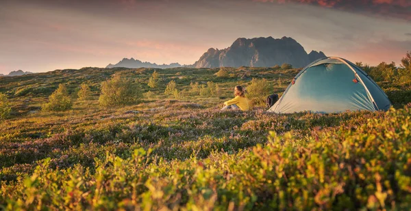 En ung kvinna är avkopplande bredvid ett tält på Lfoten öarna i — Stockfoto