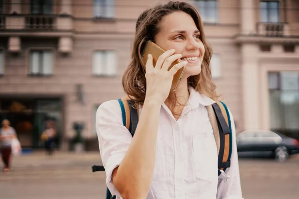 Молодая Женщина Белой Рубашке Разговаривает Смартфоне Улице Городе Транспортом Рядом — стоковое фото