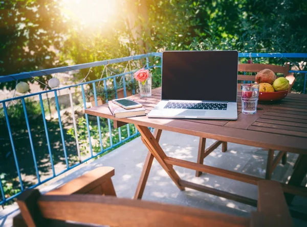 Laptop na drewnianym stole na słonecznym letnim tarasie, letnim nastroju i wakacjach w wiejskim domu — Zdjęcie stockowe