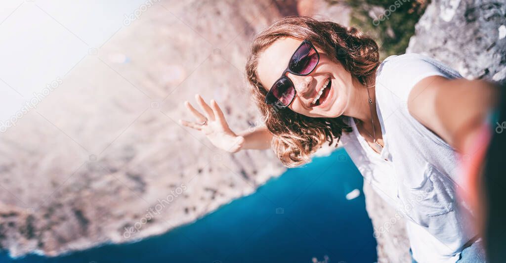 Young curly woman traveler makes selfie on a smartphone, Butterfly Valley, Turkey Oludeniz.