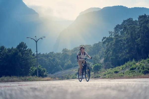 美しい若い女の子が美しい山道で自転車に乗っています 夏休みとサイクリング スポーツとアウトドア活動 — ストック写真