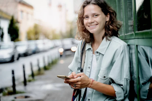 Imagen Alegre Mujer Rizada Feliz Sonriendo Usando Teléfono Móvil Mientras — Foto de Stock