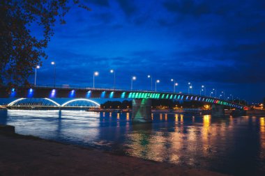 Geceleri Tuna Nehri üzerinde Petrovaradin ve Sırbistan 'ın Novi Sad kenti arasındaki gökkuşağı köprüsü. İyi geceler.