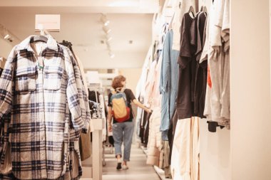 Genç bir kadın bir giyim mağazasına giriyor, alışveriş konseptiyle. Moda bölümünde tüketici