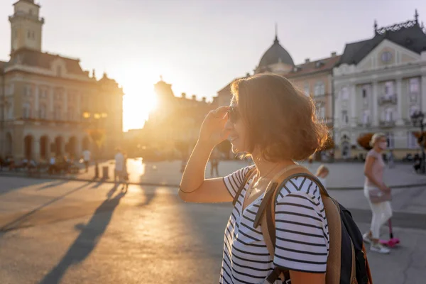 若い女性旅行者でリュックを背負ったままヨーロッパの街の広場に夕日 — ストック写真