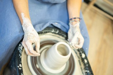 Kadın çömlekçi çarkında seramik malzeme yapmayı öğreniyor, elleri kilden yakın plan. Top shot, hobi ve yaratıcılık konsepti