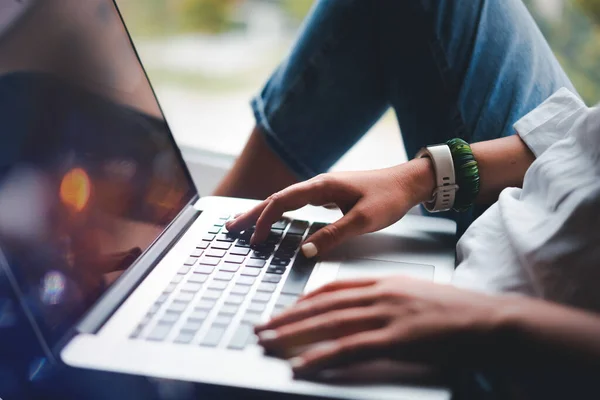 Une jeune fille en jeans travaille à la maison sur un ordinateur portable, les mains et un clavier avec un gros plan de l'écran. Enseignement technologique et pigiste — Photo