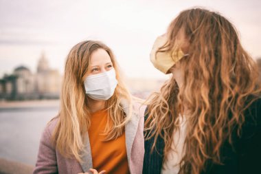 Koruyucu maskeli iki genç kadın, kendilerini izole ettikten sonra Moskova 'daki koronavirüs salgınından sonra şehirde buluşuyorlar. Sosyal uzaklık karantinası ve yeni normal yaşam tarzı