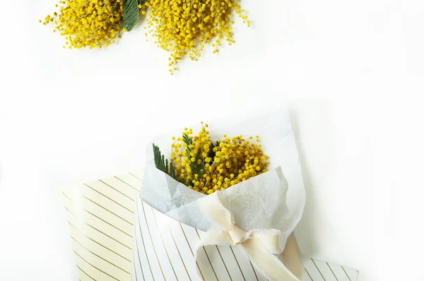 bouquet of mimosa flowers in floral striped packaging