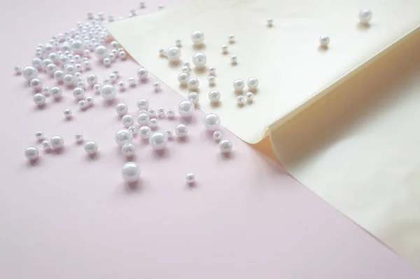 pembe arka plan üzerinde dağınık bir inci ile kağıt bir sayfa. Soyut yumuşak pastel renkler arka plan.