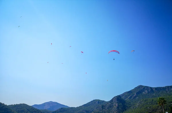 Parachuters yüksek yaz mavi gökyüzüne, Fethiye, Muğla yeşil bir tepe üzerinde uçan bir grup