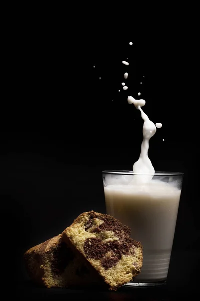 Mjölk glas stänk med kaka dessert isolerad på svart bakgrund — Stockfoto