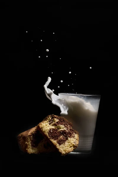 검은 배경에 고립 된 케이크 디저트와 우유 유리 스플래시 — 스톡 사진